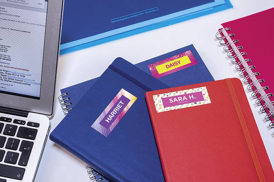 Drei Notizbücher mit den Namen Harriet, Daisy und Sara H. liegen neben einem Laptop. Ein blaues Heft ist im Hintergrund zu sehen.