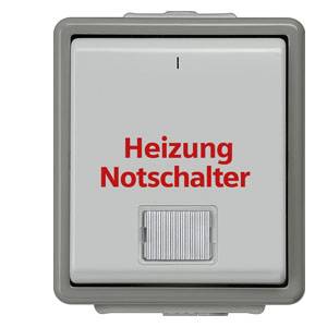 Quadratischer grauer Schalter mit roter Aufschrift 'Heizung Notschalter', darunter ein Kippschalter.