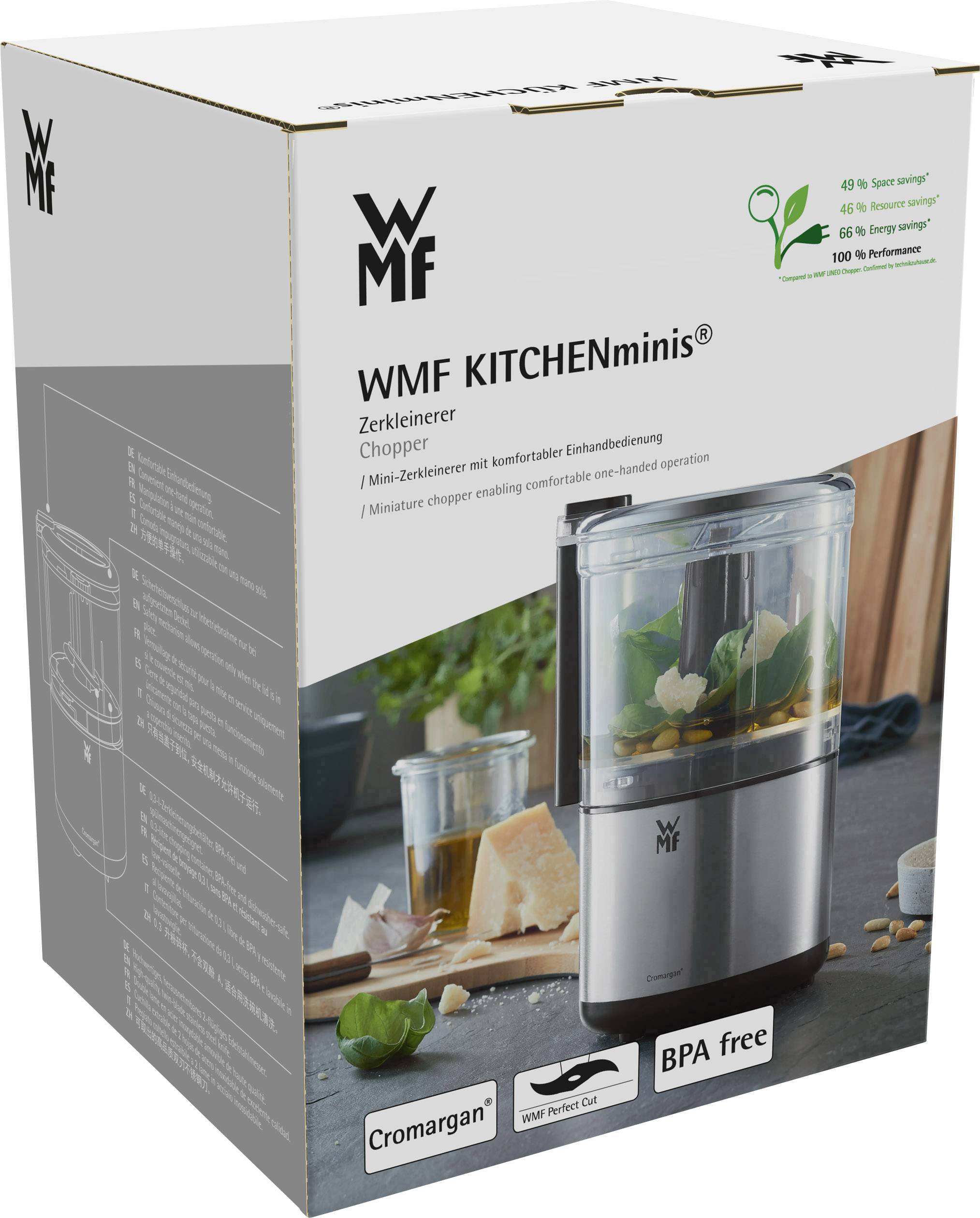 Verpackung eines WMF KITCHENminis Zerkleinerers. Zeigt das Gerät mit Lebensmittelstücken innen. Hinweise auf BPA-frei und Cromargan-Material.
