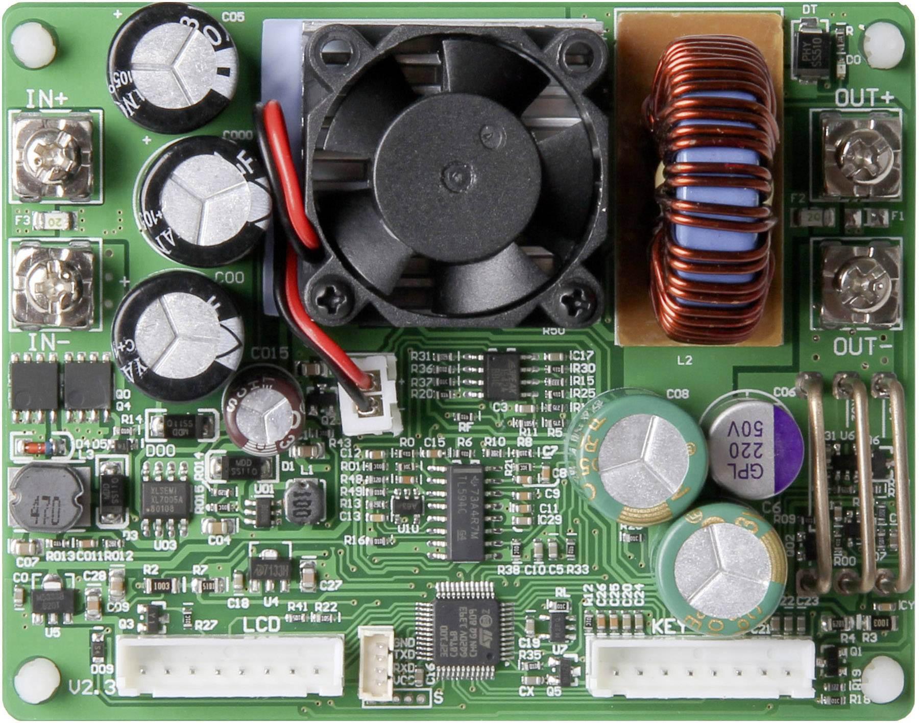 Eine grüne Leiterplatte mit mehreren Kondensatoren, Spulen, Steckverbindern und einem kleinen Lüfter, die elektronische Bauteile darstellt.