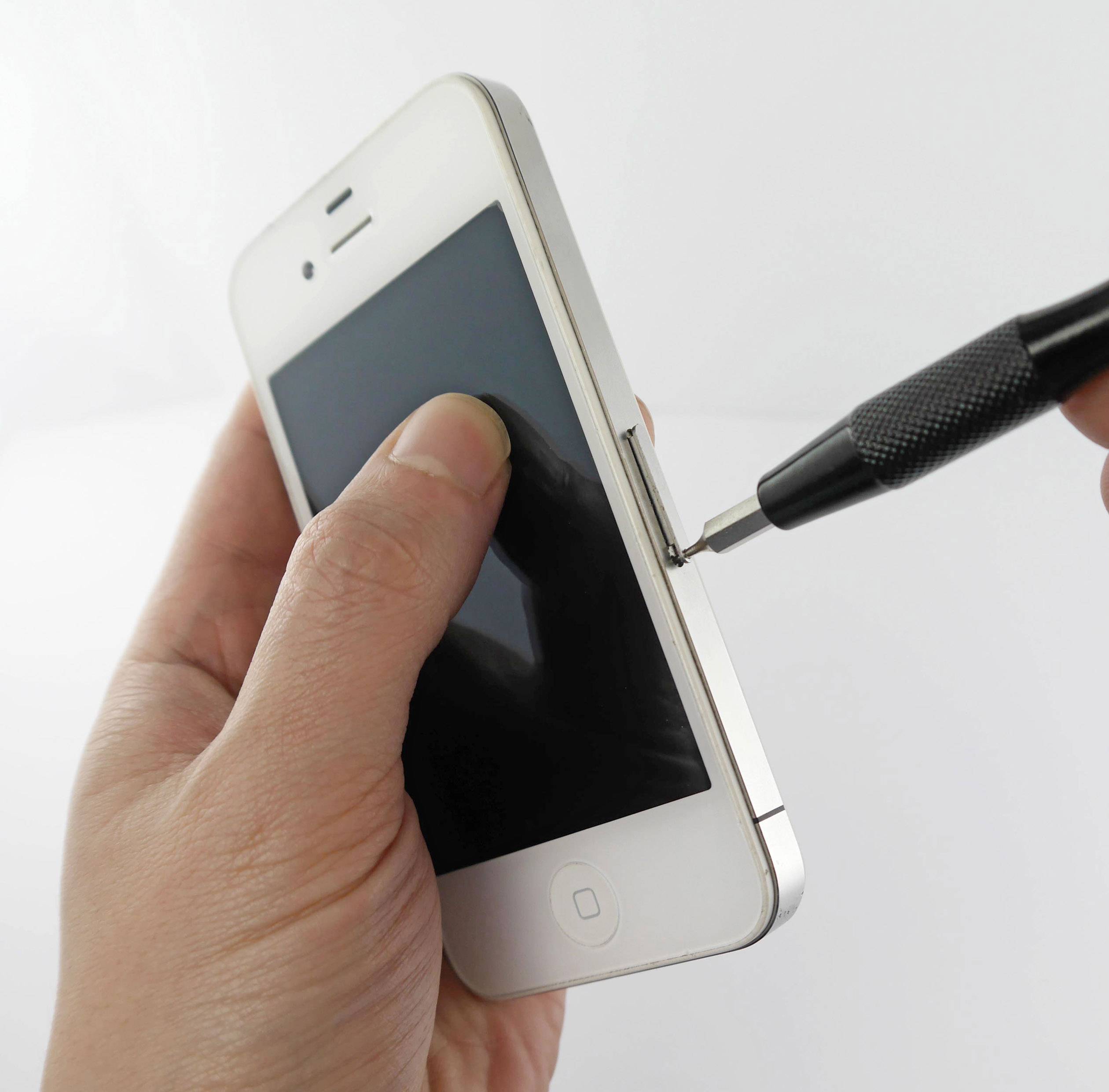 Eine Hand hält ein Smartphone, während eine andere Hand mit einem schwarzen Schraubendreher an der Seite des Telefons arbeitet.