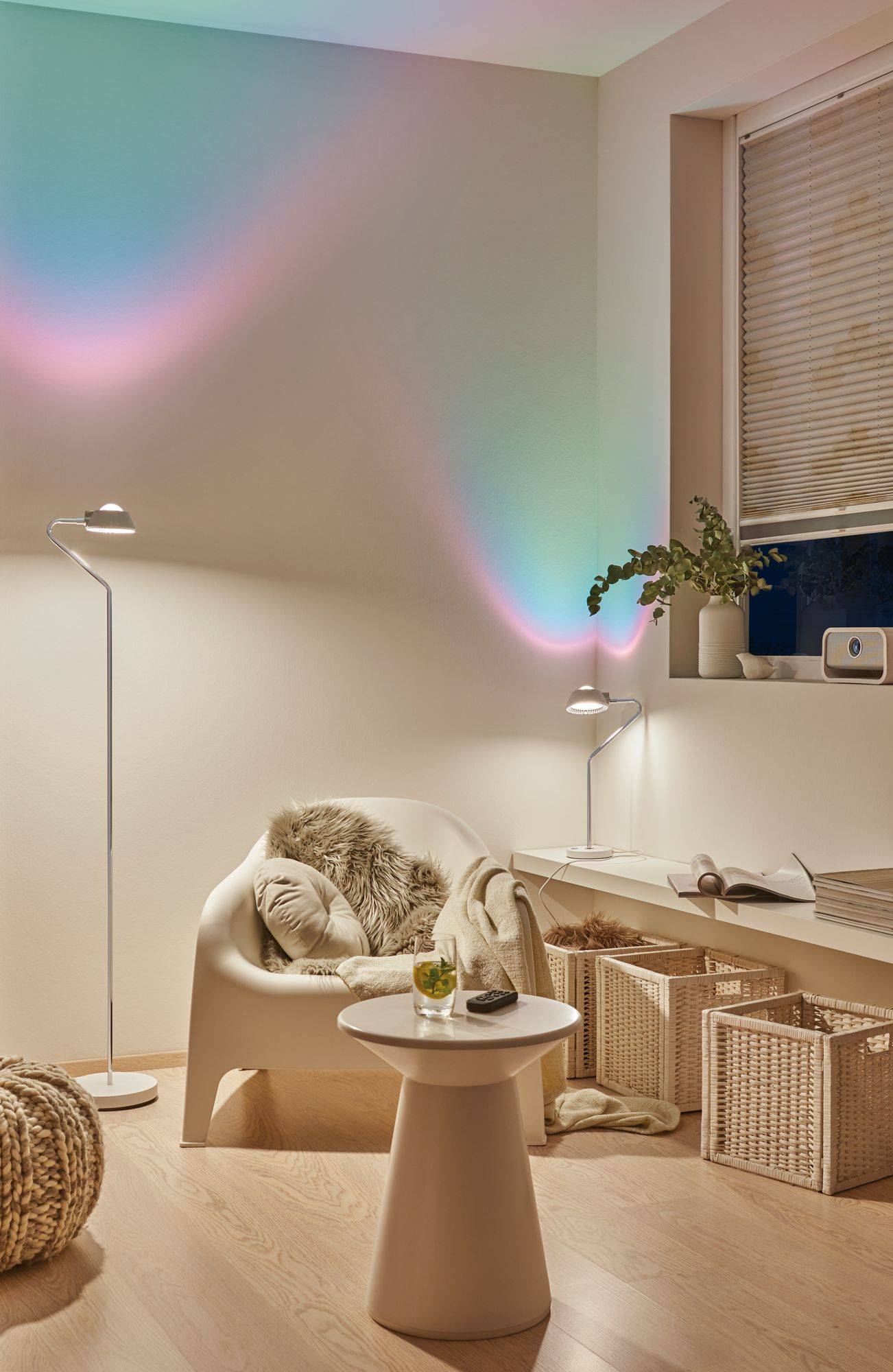 Gemütlich eingerichtetes Wohnzimmer mit Sessel, Beistelltisch, dekorativen Lichteffekten an der Wand und Pflanzen auf einem Regal.