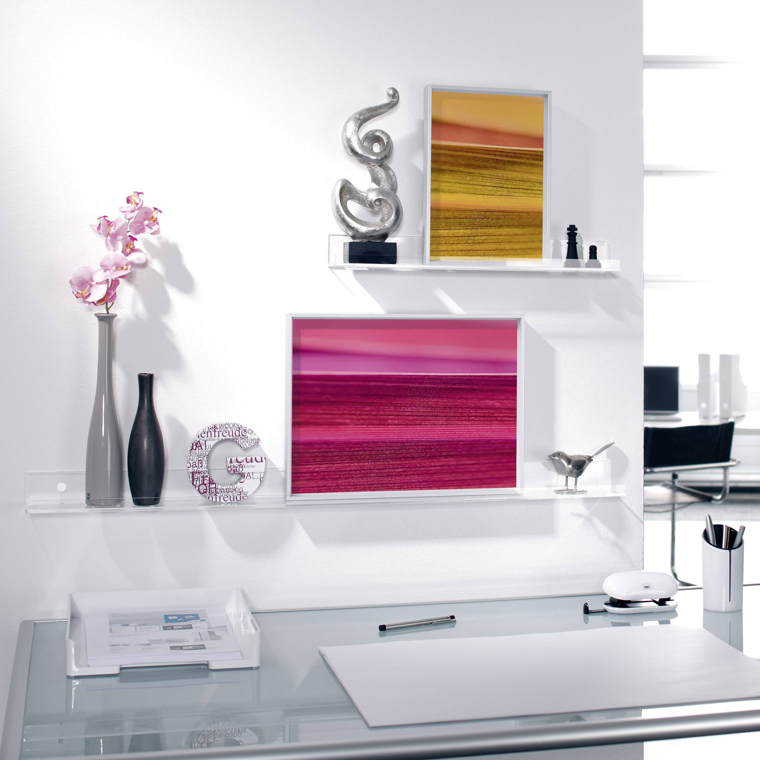 Moderner Schreibtisch mit Glasoberfläche, dekoriert mit weißen und schwarzen Vasen, rosa Kunstwerken und einer Orchidee.