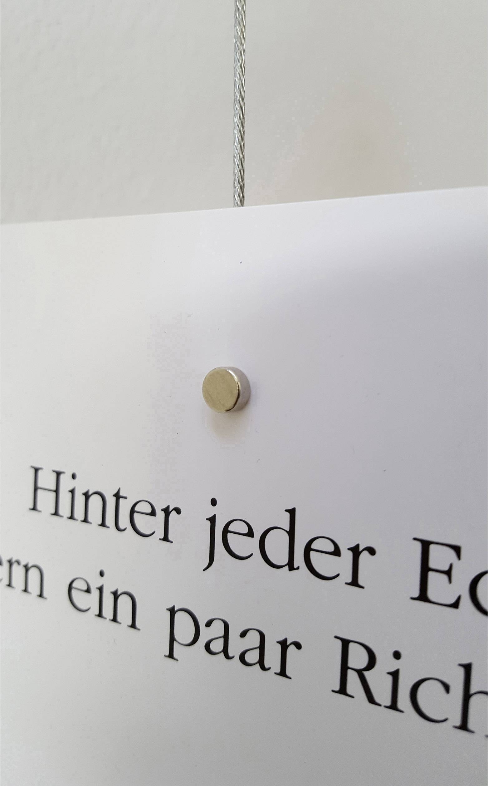 Weißes Schild an der Wand mit dem Satz 'Hinter jeder Ecke verbergen sich ein paar Richtungen'.