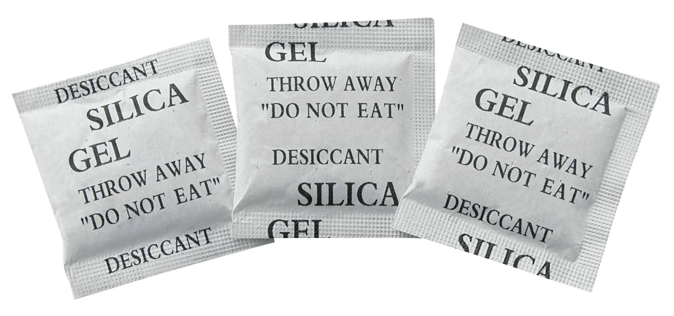 Drei Silica-Gel-Beutel mit Aufdruck 'Desiccant' und 'Throw away, do not eat'. Verwendet zur Feuchtigkeitsabsorption in Verpackungen.