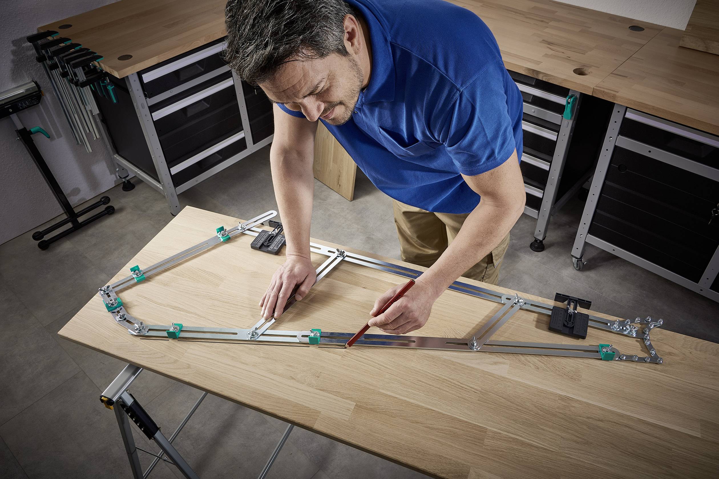 Ein Mann in einem blauen Hemd misst und markiert mit einem Bleistift auf einem Holztisch mithilfe eines Metallrahmens.