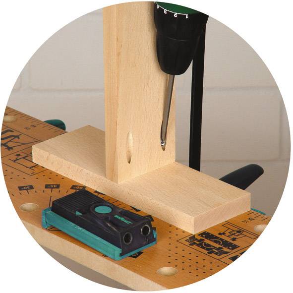 Ein Bohrer bearbeitet ein Holzstück auf einem Tisch mit Maßskala, während ein Winkelmesser darauf liegt.