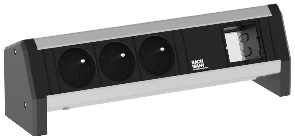 Steckdosenleiste mit drei schwarzen Steckplätzen und einem RJ45-Anschluss auf einem Tisch montiert, Firmenlogo 'Bachmann'.