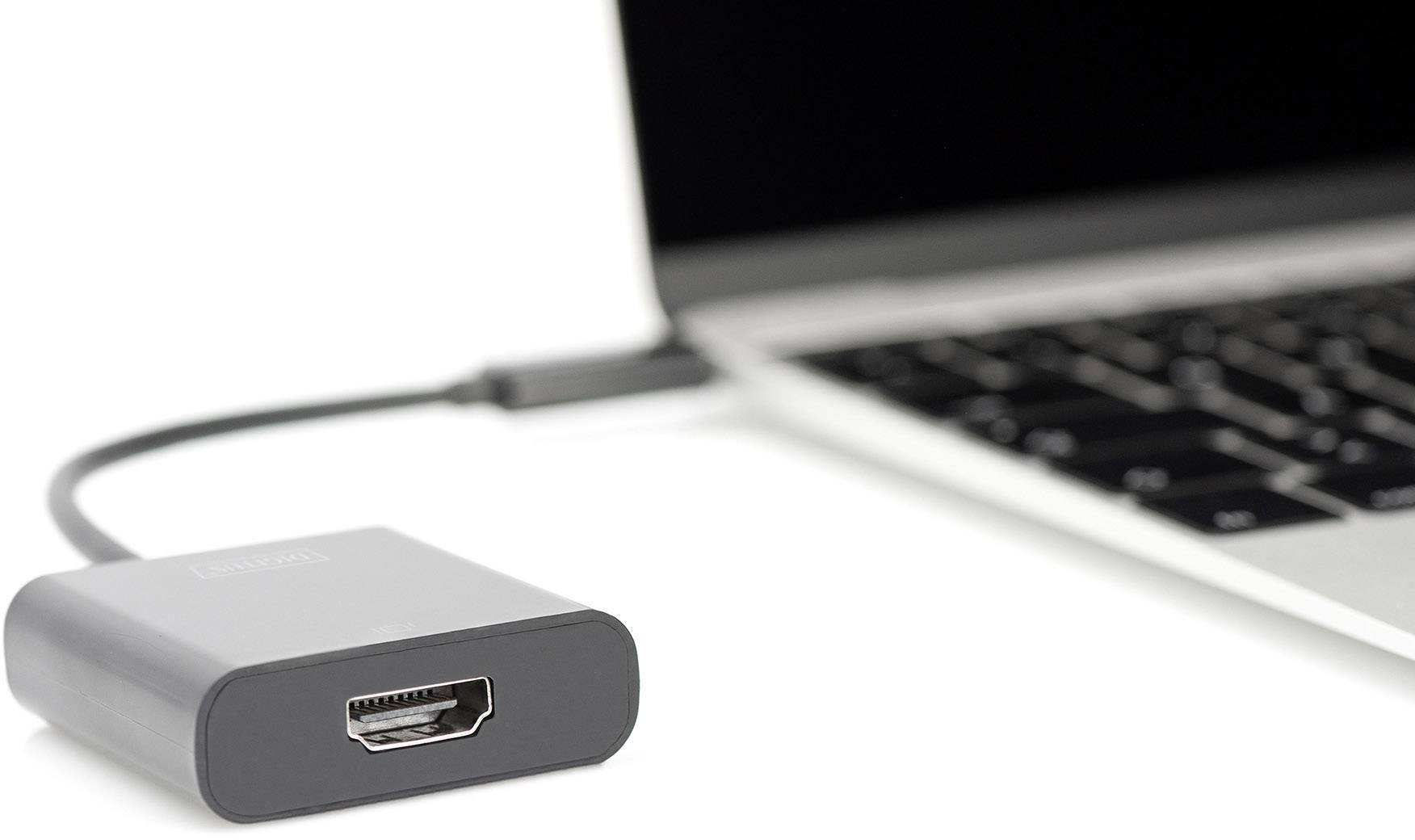 Ein schwarzer HDMI-Adapter ist mit einem Laptop verbunden. Der Laptop ist teilweise sichtbar, mit Fokus auf die Tastatur.