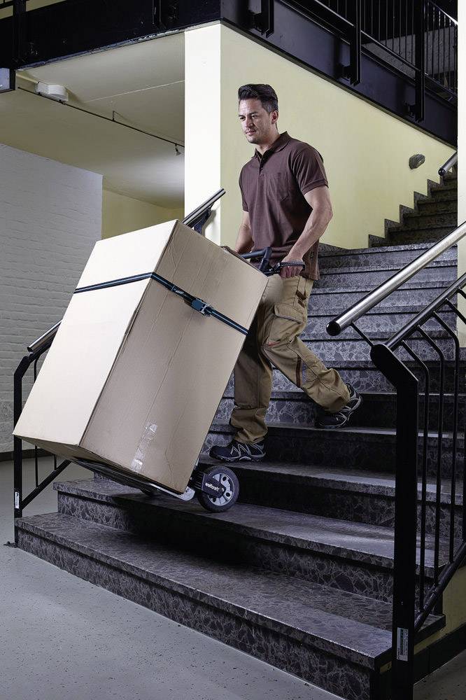 Mann transportiert einen großen Karton mit einem Treppensteigerwagen eine Treppe hinunter.