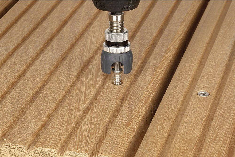 Ein Schraubendreher zieht eine Schraube in eine Holzplatte ein, die gerillt ist.