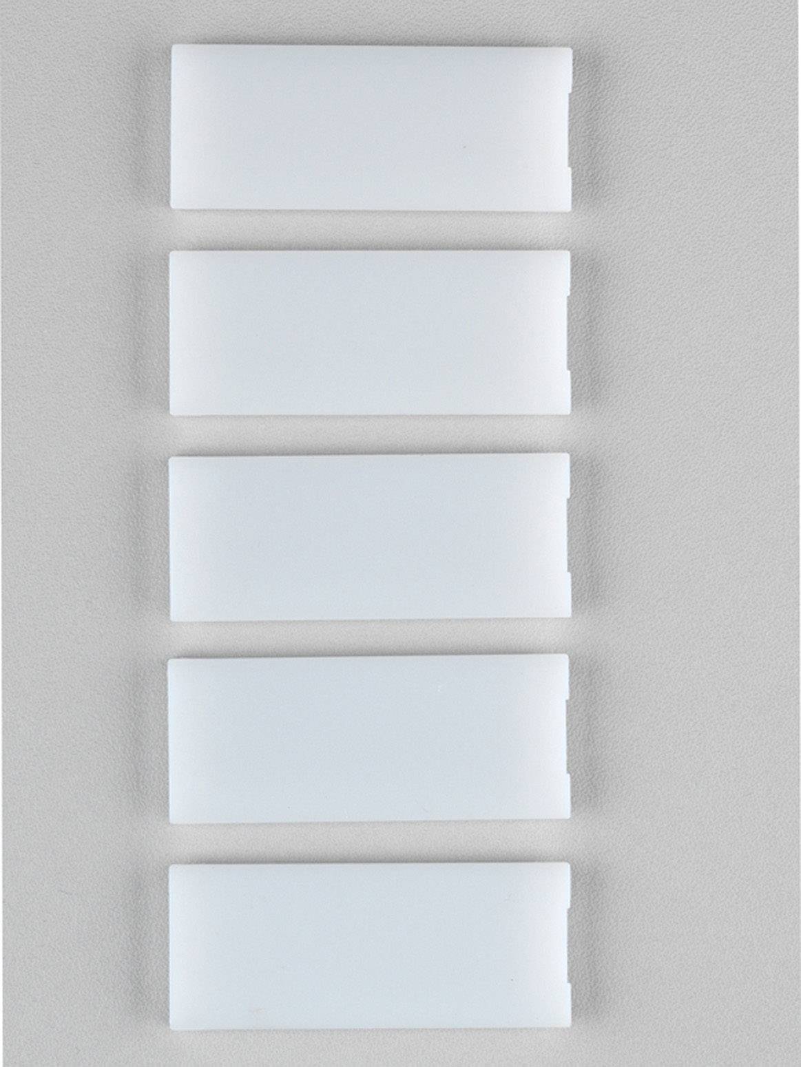 Fünf weiße rechteckige Schalter oder Platten nebeneinander angeordnet auf einer hellgrauen Wand.