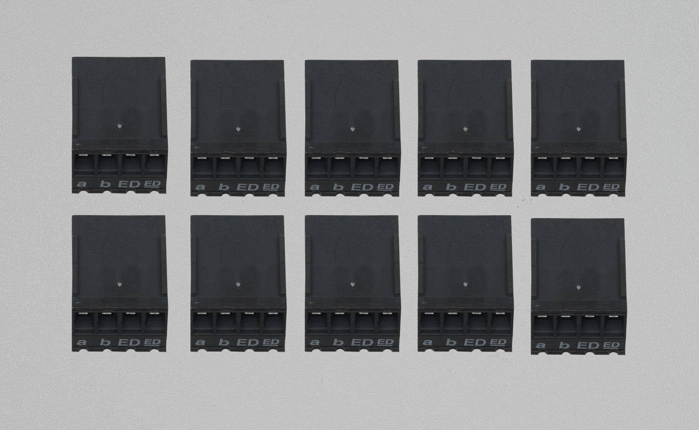 Zehn schwarze Kunststoffstecker, in zwei Reihen angeordnet, auf grauem Hintergrund. Jeder Stecker hat vier Pins.