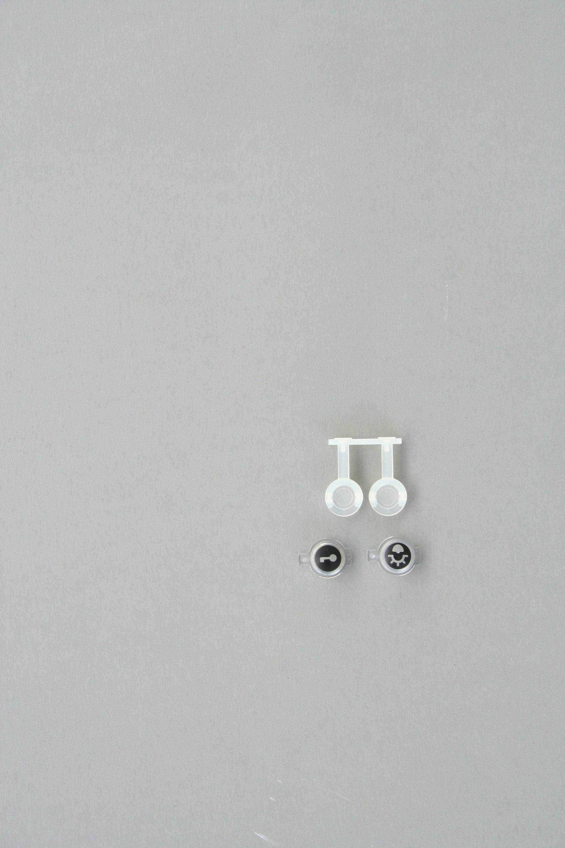 Zwei Sets von Augen mit Plastikbefestigungen auf grauem Hintergrund. Ein Paar hat schwarze Pupillen, das andere weiße Kreuze.