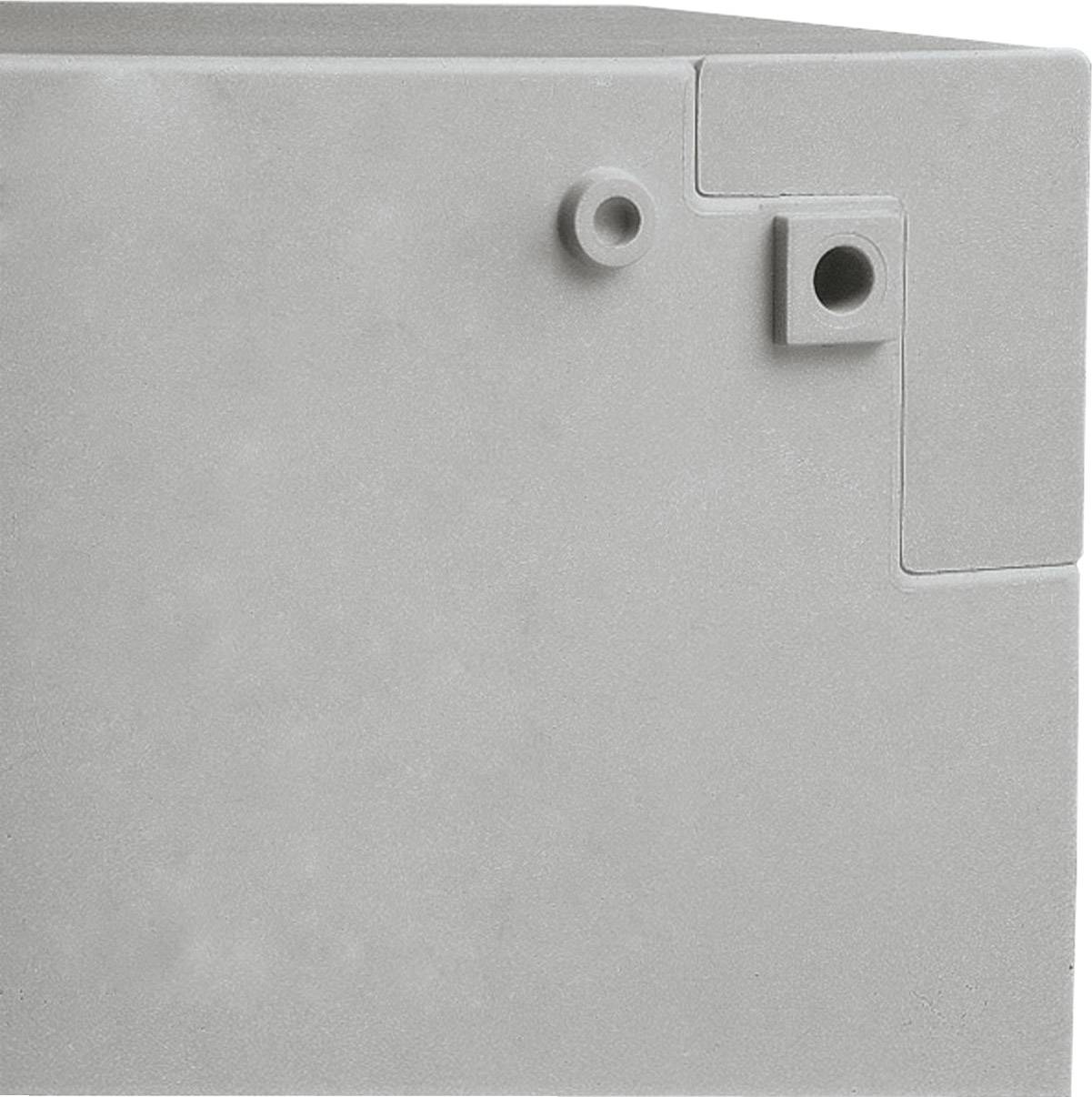 Grauer, geometrisch geformter Gegenstand mit hervorstehenden Teilen und kreisförmiger Öffnung an der Vorderseite.