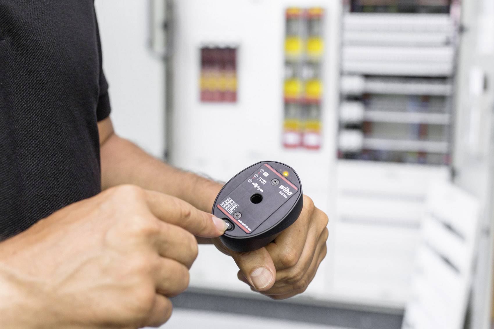 Eine Person überprüft mit einem elektrischen Prüfgerät die Spannung in einem Schaltschrank.