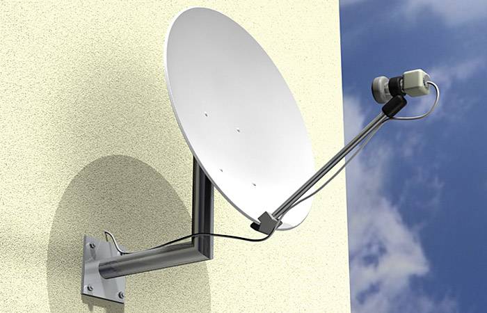 Satellitenschüssel an einer Hauswand befestigt, zeigt in Richtung Himmel, klare Sicht auf blauen Himmel mit einigen Wolken.