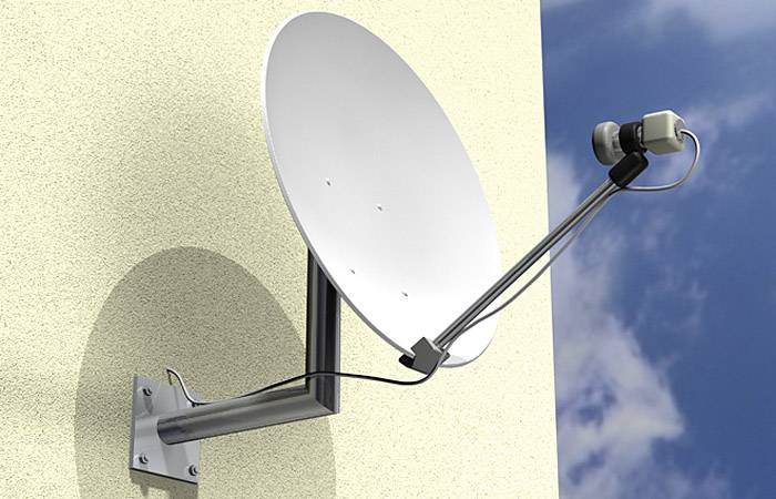 Satellitenschüssel an einer gelben Wand montiert, ausgerichtet zum Empfang von Satellitensignalen. Blauer Himmel im Hintergrund.