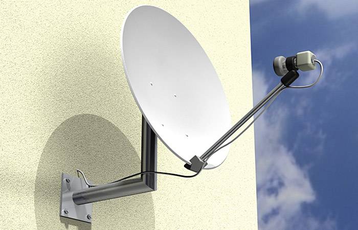 Satellitenschüssel an einer Hauswand montiert, zeigt nach oben in den blauen Himmel.