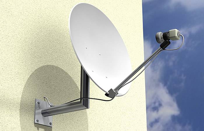 Satellitenschüssel an der Wand montiert, zeigt zum Himmel. Klarer Himmel mit ein paar Wolken im Hintergrund.