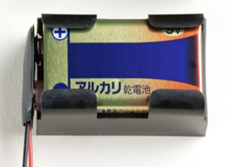 Eine 9V-Alkalibatterie in einem schwarzen Batteriehalter, an dem ein rotes und ein schwarzes Kabel befestigt sind.