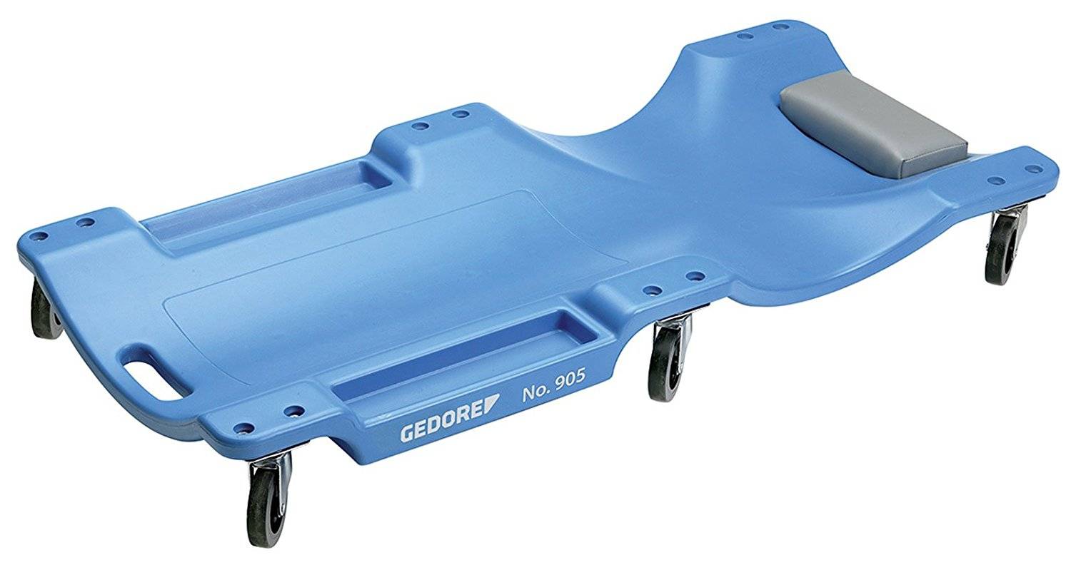 Ein blauer Werkstattliegewagen mit sechs Rollen, einer gepolsterten Kopfstütze und Griffen an den Seiten. Markenname 'GEDORE' sichtbar.