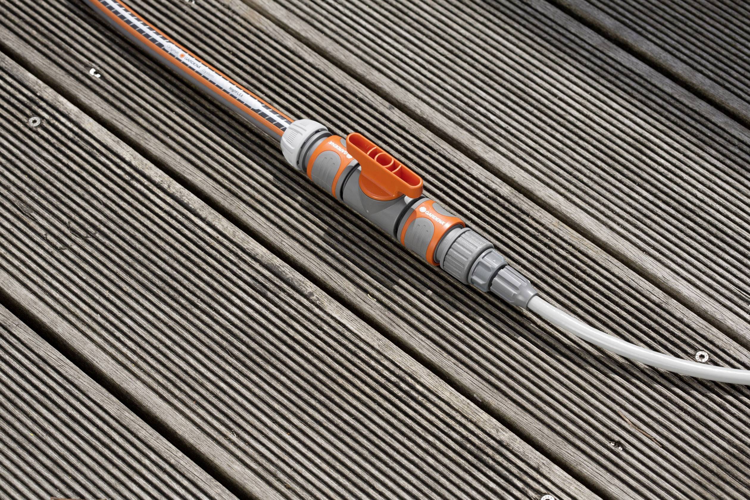 Ein grauer Schlauch mit orangefarbenen Verbindungsstücken liegt auf einem Holzdeck.