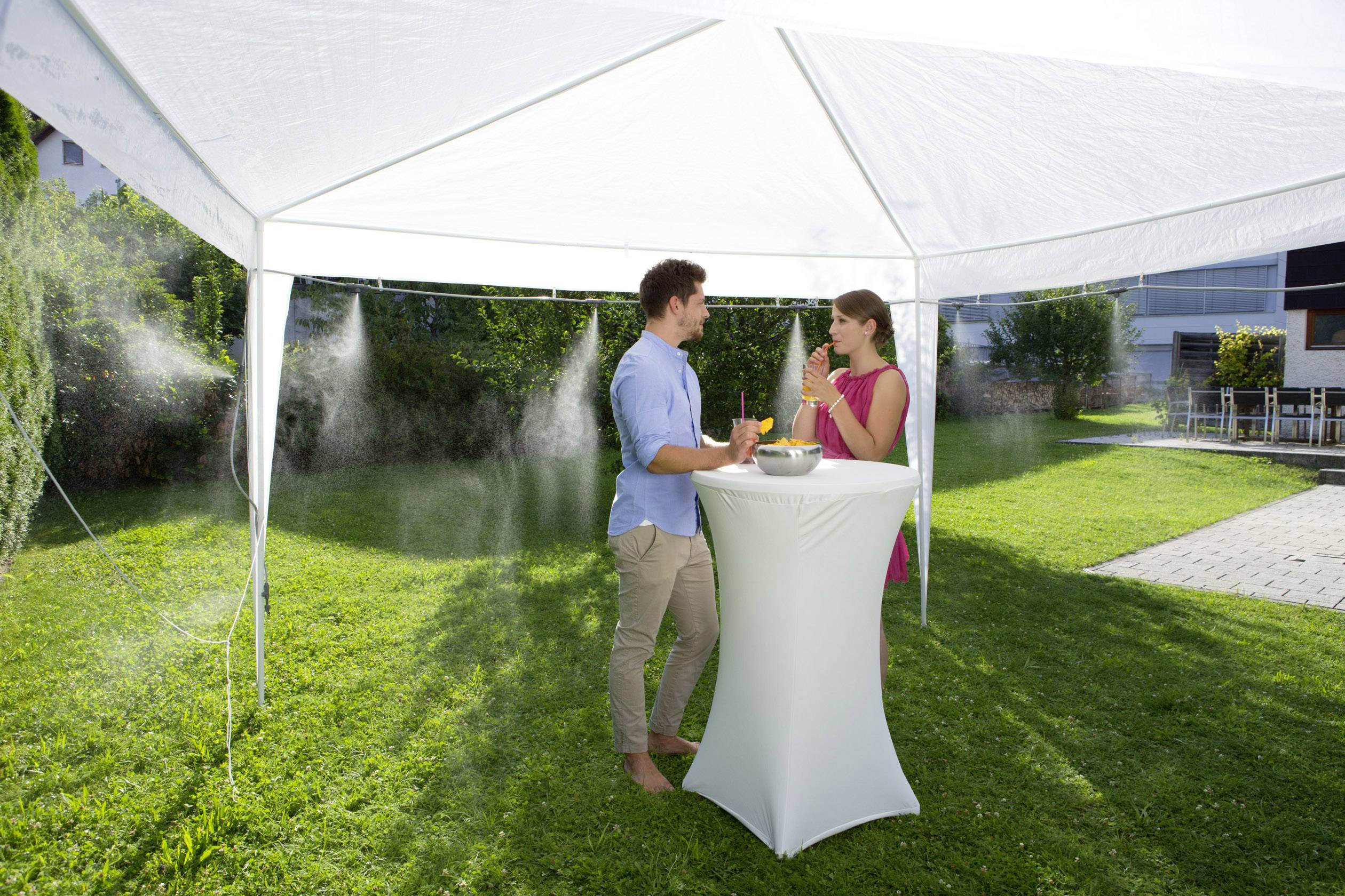 Ein Mann und eine Frau stehen unter einem weißen Pavillon in einem Garten, trinken Erfrischungsgetränke und unterhalten sich.