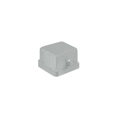 Ein kleiner grauer Metallgegenstand mit quadratischer Basis und abgerundeten Ecken auf einer weißen Fläche.