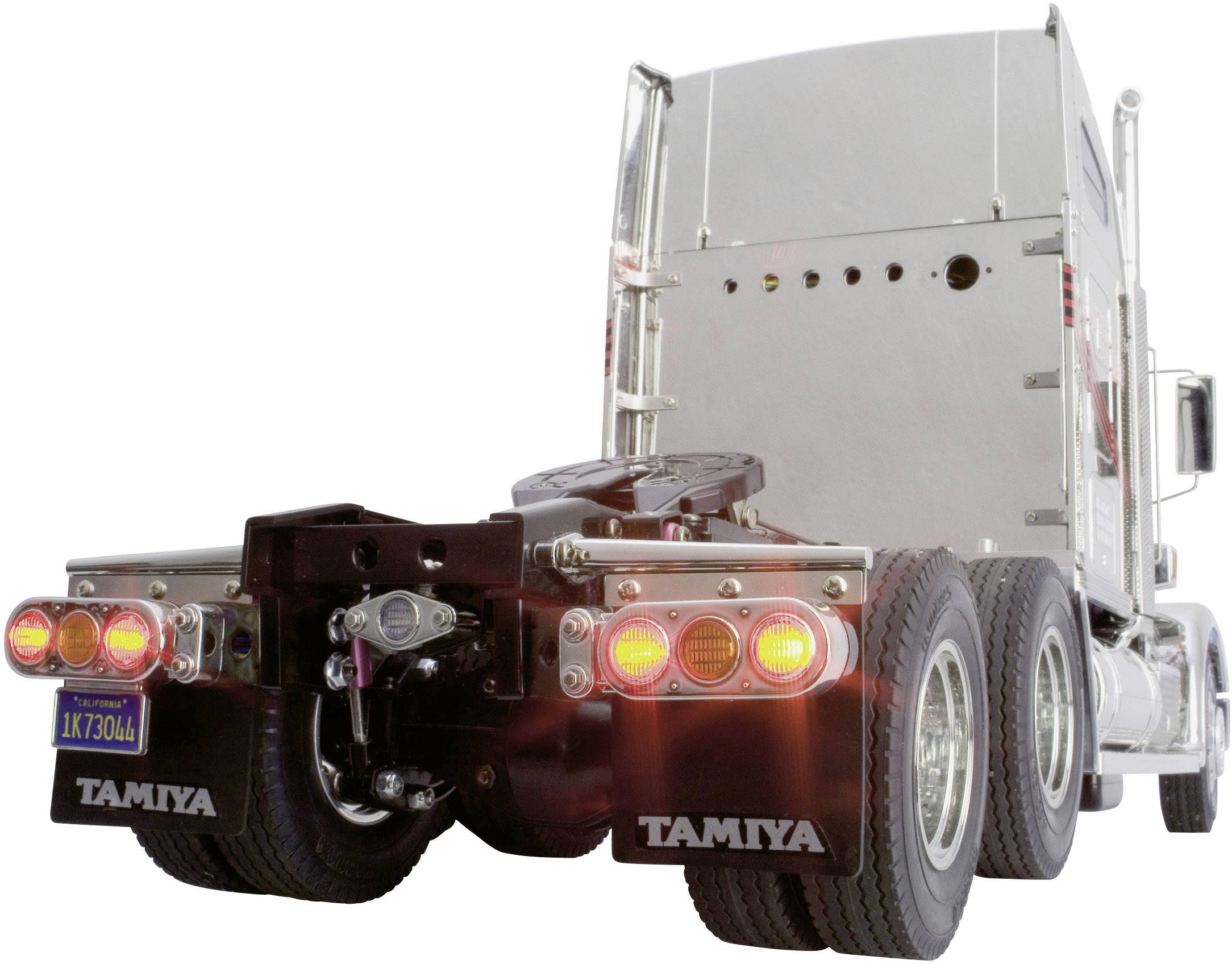 Ein silberner Modell-Lkw von Tamiya mit leuchtenden Rücklichtern, erkennbar an der Markenbezeichnung auf den Spritzschutzklappen.