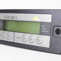 Das Bild zeigt ein digitales Anzeigegerät mit der Aufschrift 'FOX-MD1'. Es hat Knöpfe für verschiedene Funktionen, vermutlich zur Gerätesteuerung.