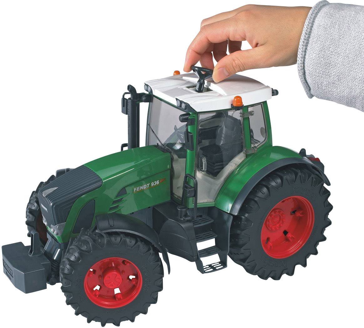 Eine Hand betätigt eine Spielzeugtraktor in grün mit roten Rädern, simuliert landwirtschaftliche Arbeiten.