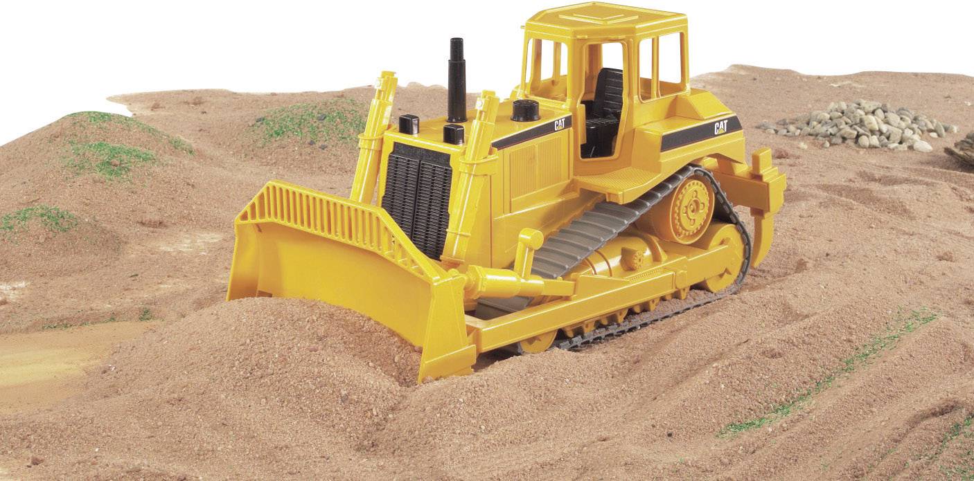 Ein gelber Bulldozer bewegt Schotter auf einer Baustelle. Im Hintergrund sind Erd- und Schotterhügel sichtbar.