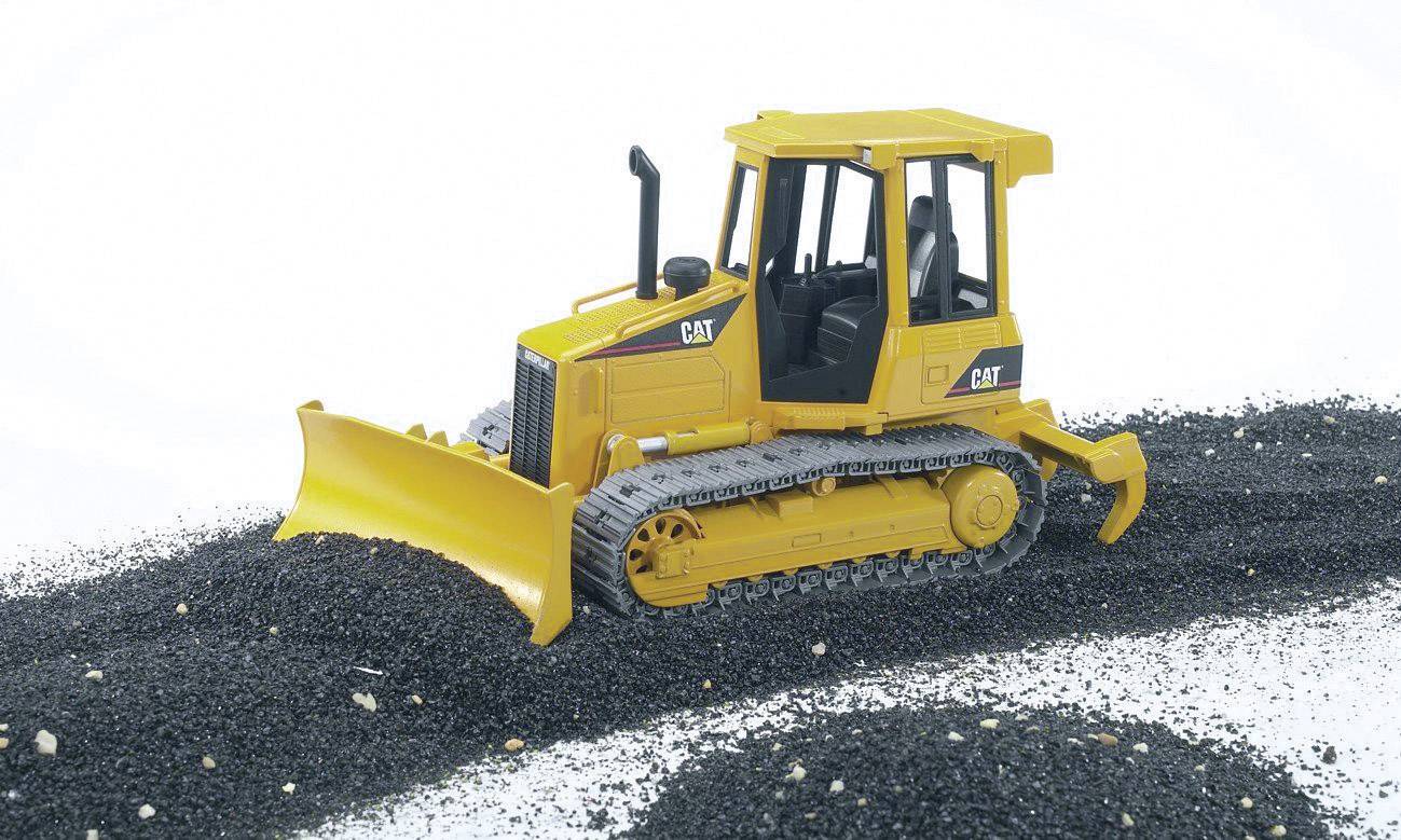 Ein gelber Modell-Bulldozer auf einem Haufen schwarzem Sand. Der Bulldozer hat Raupenketten und eine große Schaufel vorne.