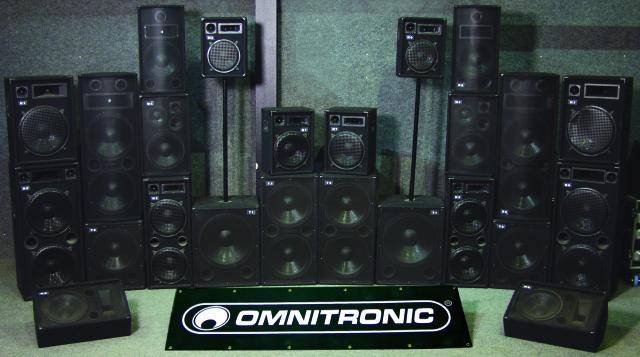 Eine Sammlung von schwarzen Lautsprechern verschiedener Größen von 'Omnitronic', symmetrisch angeordnet vor einer Wand.