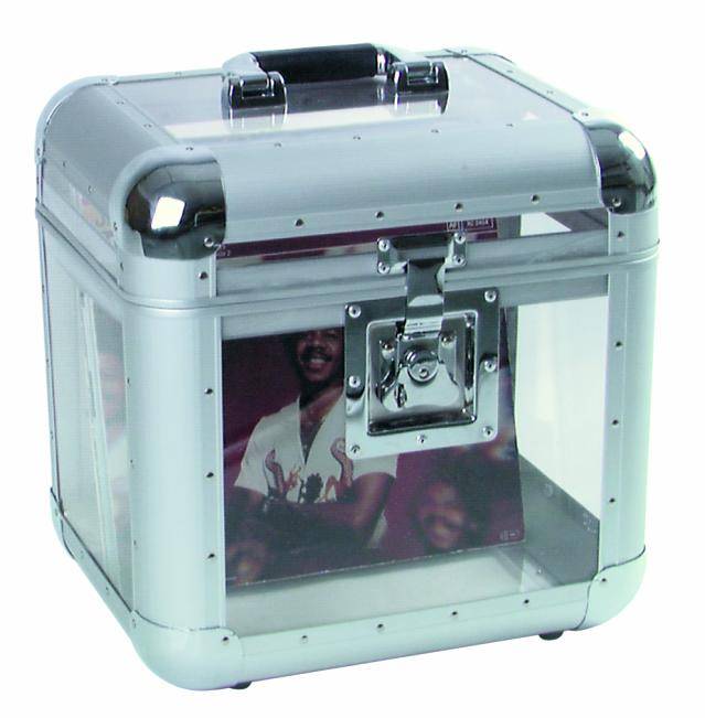 Ein transparenter, würfelförmiger Koffer mit Metallecken. Innen sichtbar ist ein Bild von einer Person in weißem Hemd.