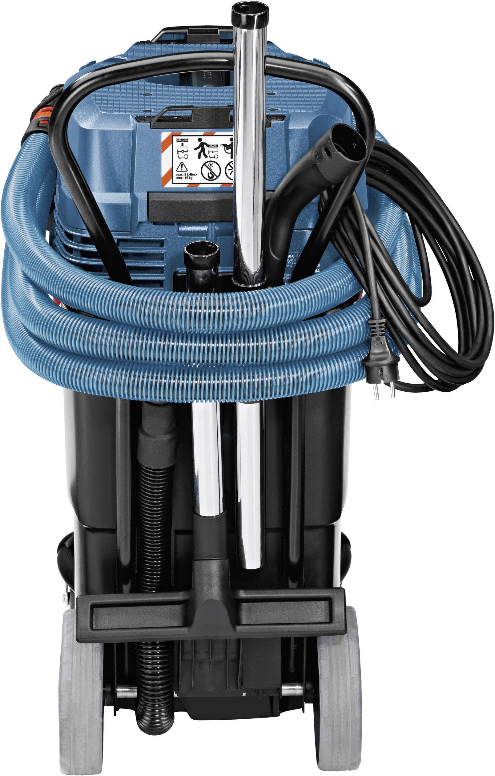 Staubsauger mit blauem Schlauch und schwarzem Gehäuse, zwei Metallrohre, Stromkabel und Räder. Vorn befindet sich ein Warnhinweis.