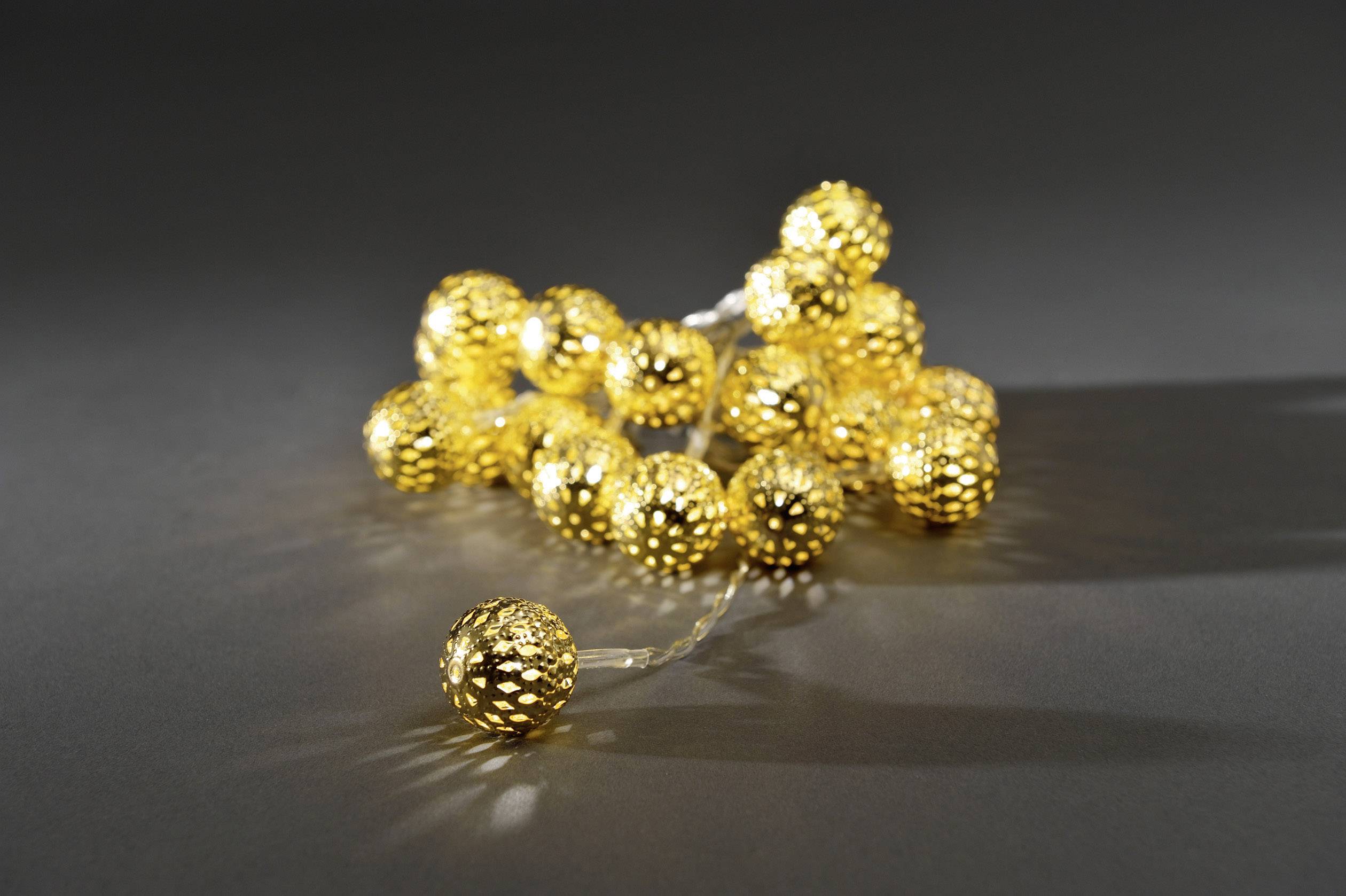 Eine Lichterkette mit goldfarbenen Kugeln liegt auf einer dunklen Oberfläche, erstrahlt in warmem Glanz und erzeugt stimmungsvolle Beleuchtung.