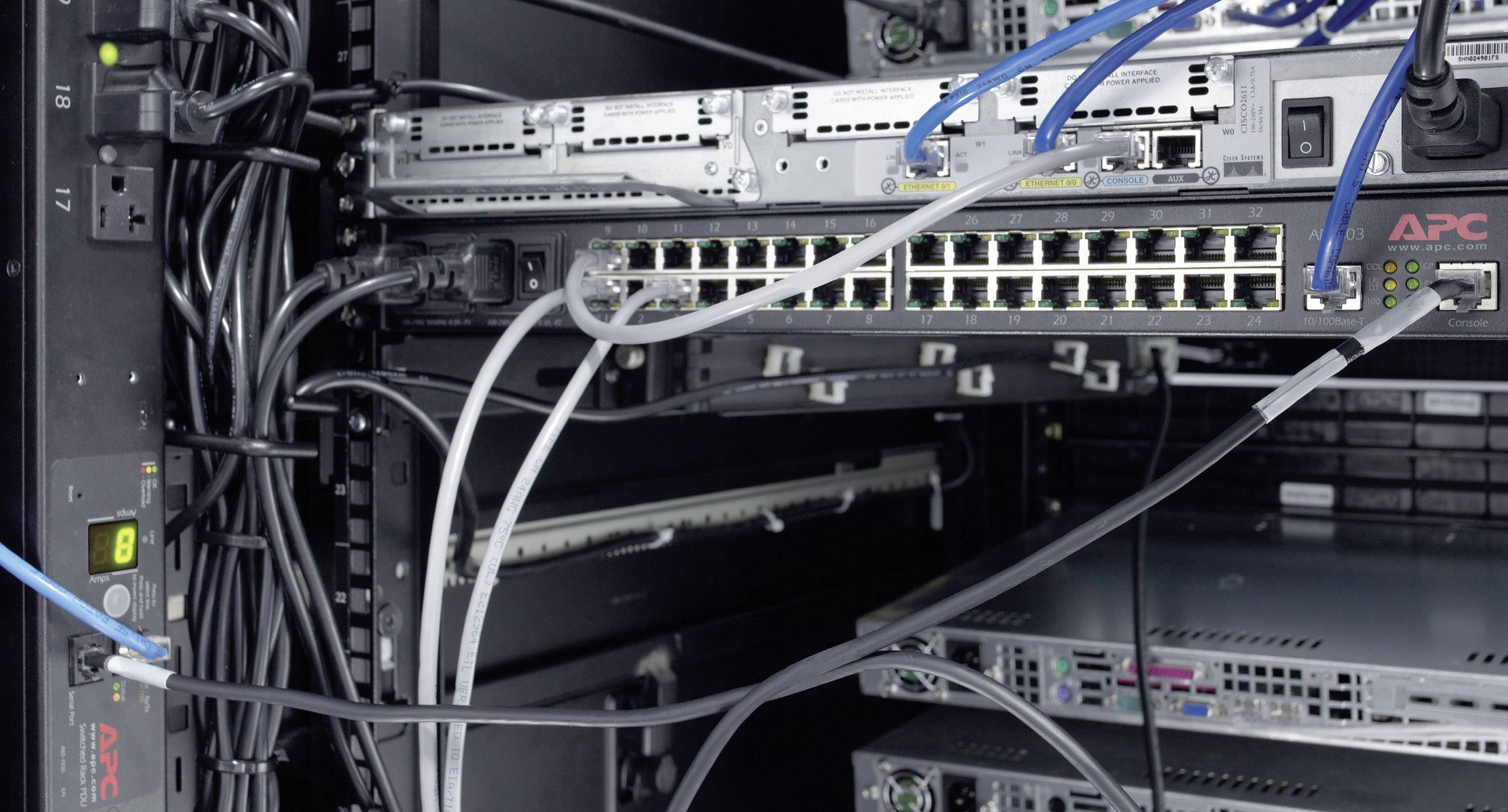 Ein Serverrack mit Kabeln und Netzwerkgeräten. Einige Kabel sind mit einem Switch verbunden, der Teil eines Netzwerksystems ist.