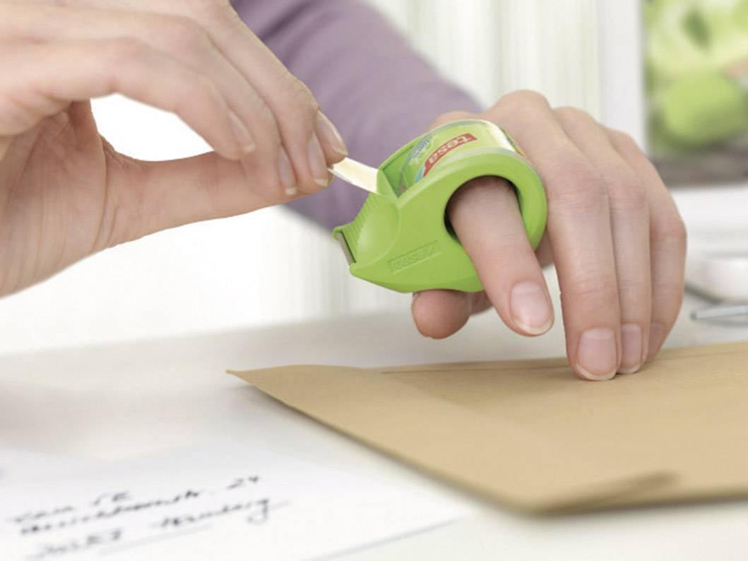 Eine Hand benutzt einen Fingerabroller, um Klebeband von einer Rolle auf einen Briefumschlag zu kleben.