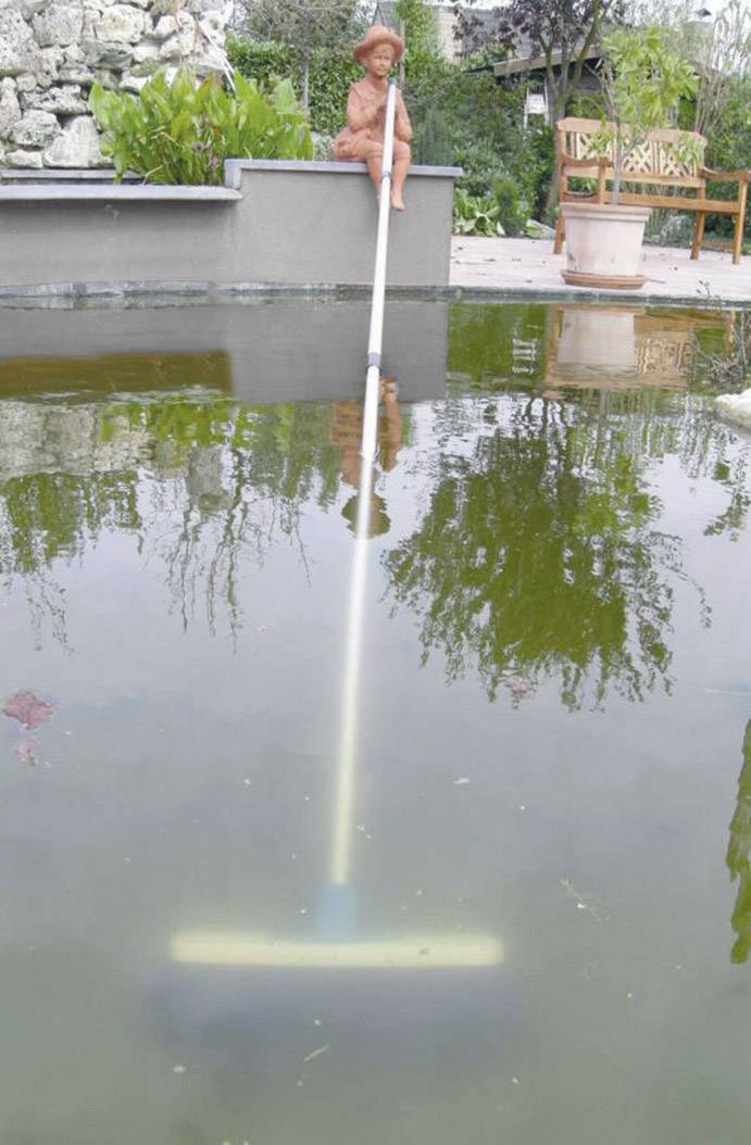 Tonfigur am Beckenrand eines Teiches mit Laub, nutzt Kescher um Blätter aus dem Wasser zu entfernen. Im Hintergrund Gartenmöbel.