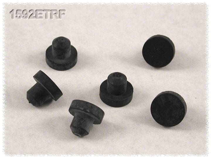 Sechs schwarze Gummifüße liegen verstreut auf einer hellen Oberfläche. Oben links steht der Text '1592ETRF'.