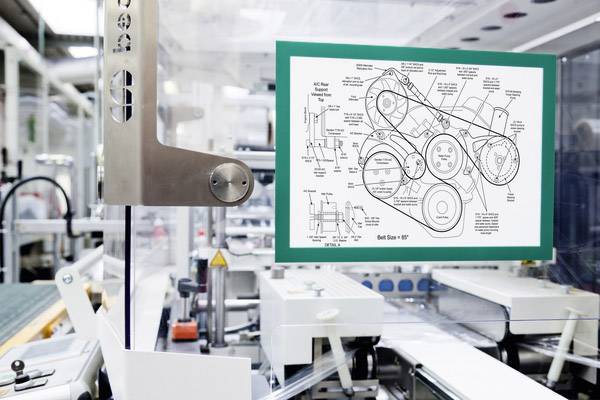 Eine Industriemaschine in einer Fabrik, die mit einem technischen Diagramm einer Riemenscheibenanordnung auf einem Bildschirm arbeitet.