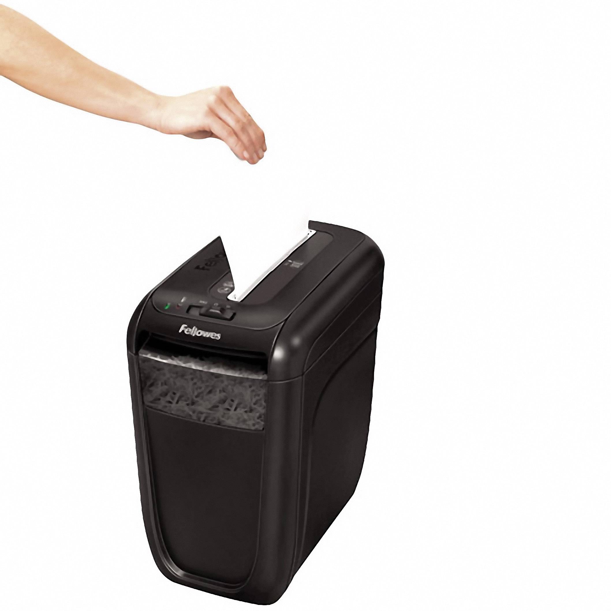 Eine Hand schiebt ein Blatt Papier in einen schwarzen Aktenvernichter. Der Aktenvernichter ist auf einem weißen Hintergrund platziert.