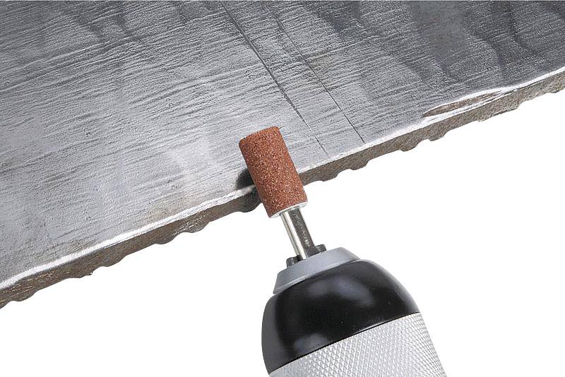 Werkzeug mit rotierender Schleifscheibe schleift eine Metallkante, glättet die Oberfläche.