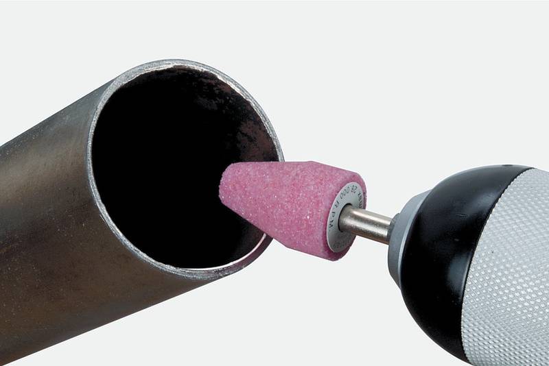 Bohrer mit pinkem Schleifaufsatz bearbeitet Innenfläche eines Metallrohrs, zeigt Einsatz von Schleifwerkzeug bei Metallarbeiten.