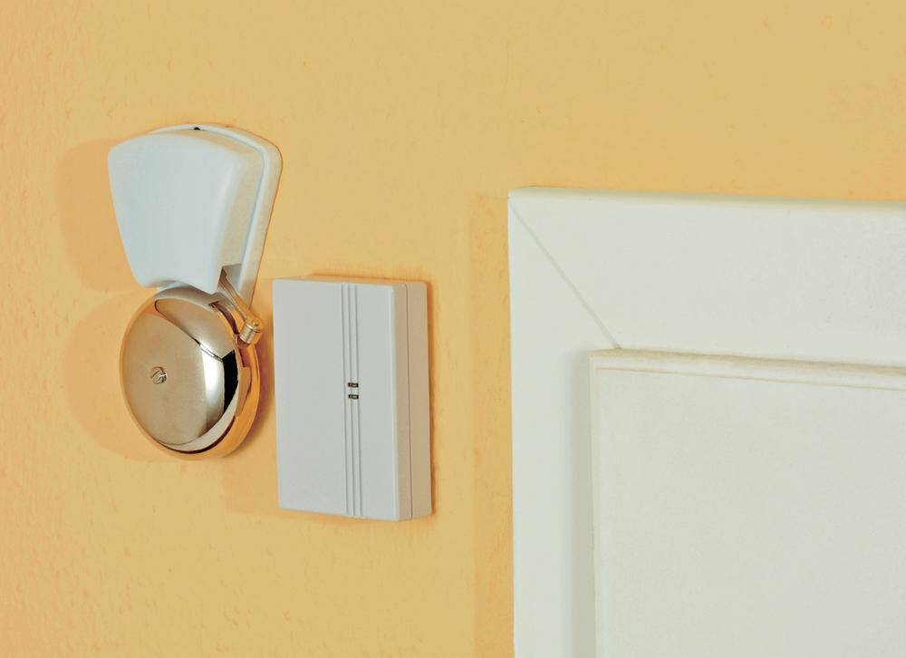Eine Türklingel und ein Schalter an einer orangefarbenen Wand neben einem weißen Türrahmen.