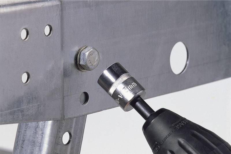 Schraubenschlüsselaufsatz auf einer Bohrmaschine zieht eine Sechskantschraube an einem Metallrahmen an.