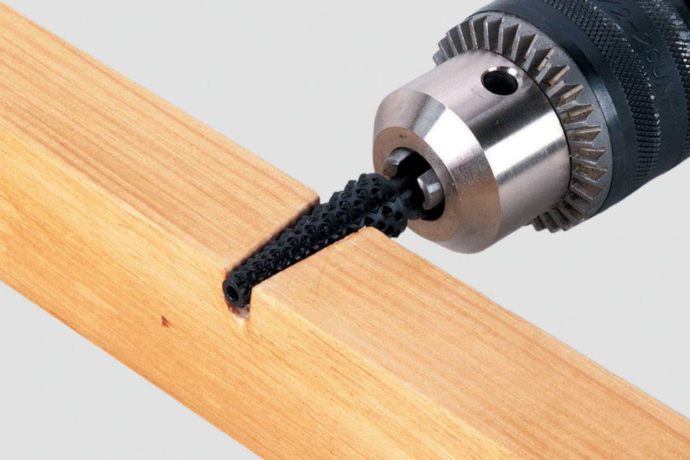 Eine Bohrmaschine bearbeitet ein Stück Holz mit einem speziellen Aufsatz, der Material präzise entfernt.