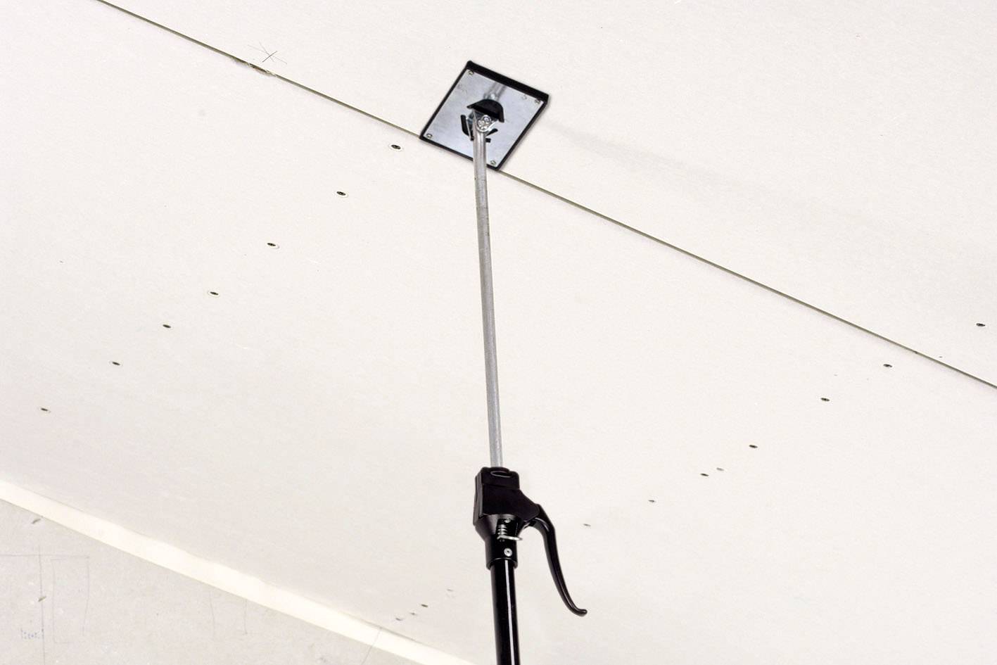 Ein Stützstab hält eine Gipskartonplatte an einer Decke fest. Der Stab hat eine Hebelmechanik zur Stabilisierung.